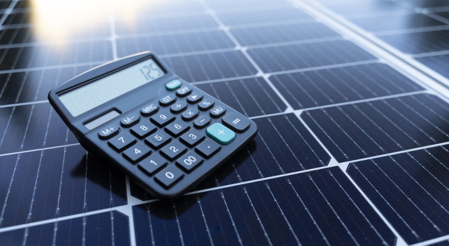 Image of a calculator on a solar panel representing the concept of saving energy with renewable energy